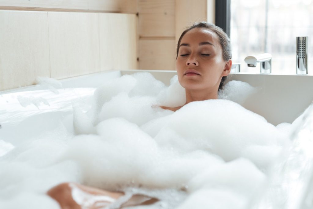 How To Make A DIY Spa Kit Without Breaking The Bank: 8 Ways; Beautiful young woman with closed eyes resting and relaxing in bathtub