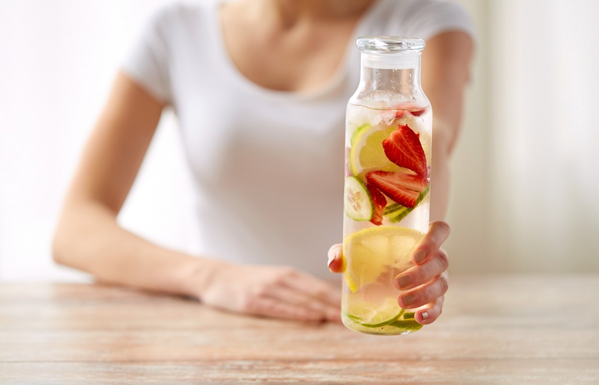 21 Invigorating Spa Water Recipes For Instant Energy; close up of woman with fruit water in glass bottle