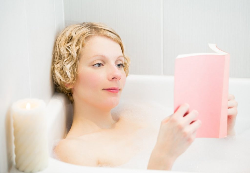 15 Mind Blowing Home Spa Ideas For Complete Pampering; Happy young woman relaxing and reading a book in the bath