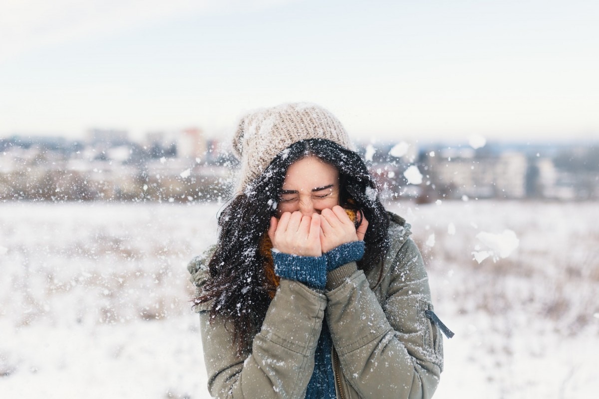 Smiling woman feeling cold snowflakes on her face during a snow