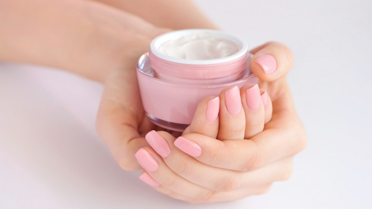 10 Ways To Repair Damaged Nails After Gel And Acrylics; Hands of a woman with pink manicure with cream